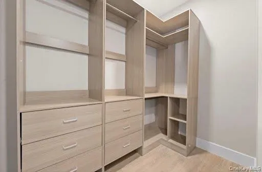 walk in closet system featuring natural wood-finish storage, multiple shelving units, integrated drawers with modern pulls, and corner shelving for optimized organization walk in closet system featuring natural wood-finish storage, multiple shelving units, integrated drawers with modern pulls, and corner shelving for optimized organization