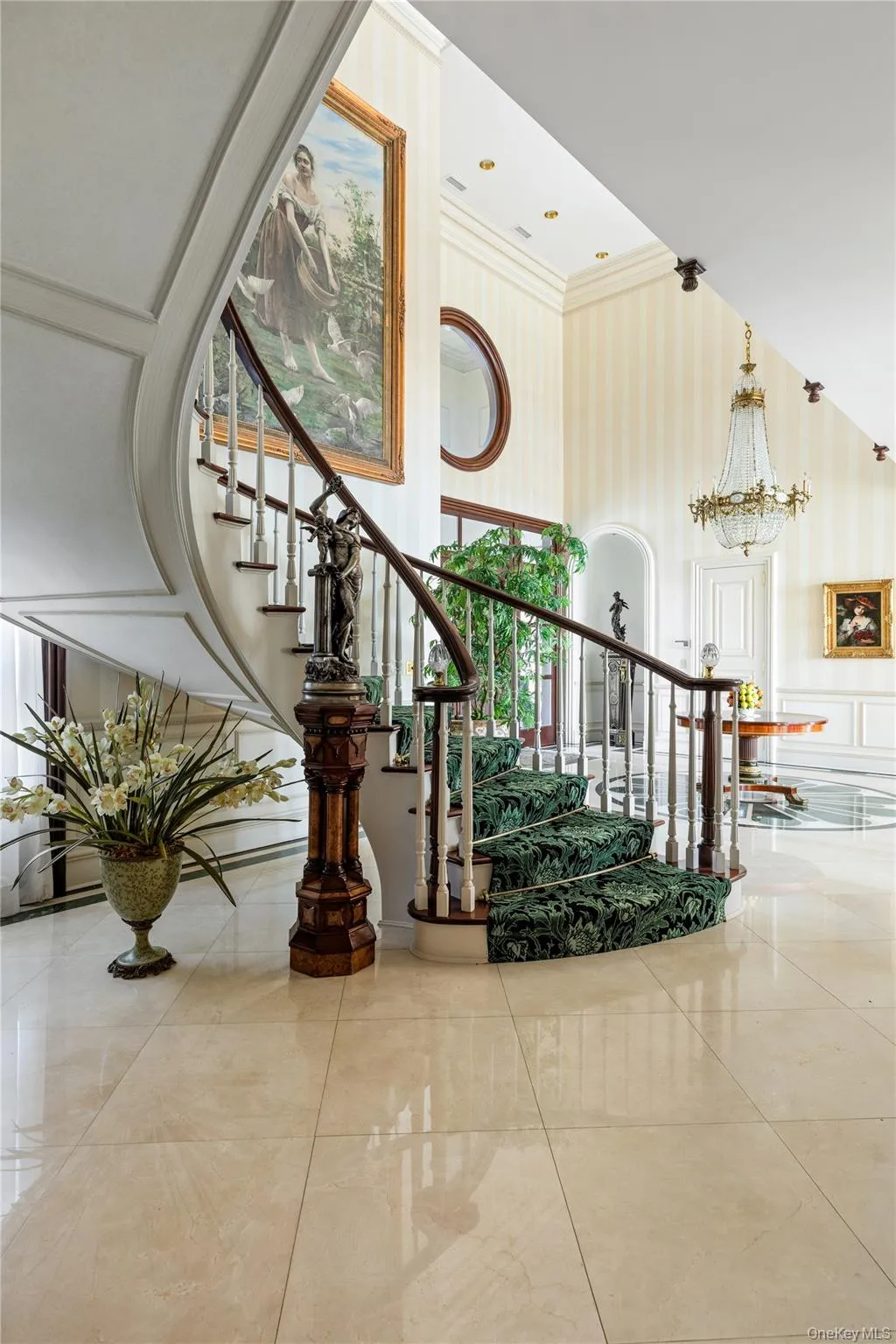 Grand foyer featuring a curved staircase with a dark wood handrail and white balusters Grand foyer featuring a curved staircase with a dark wood handrail and white balusters