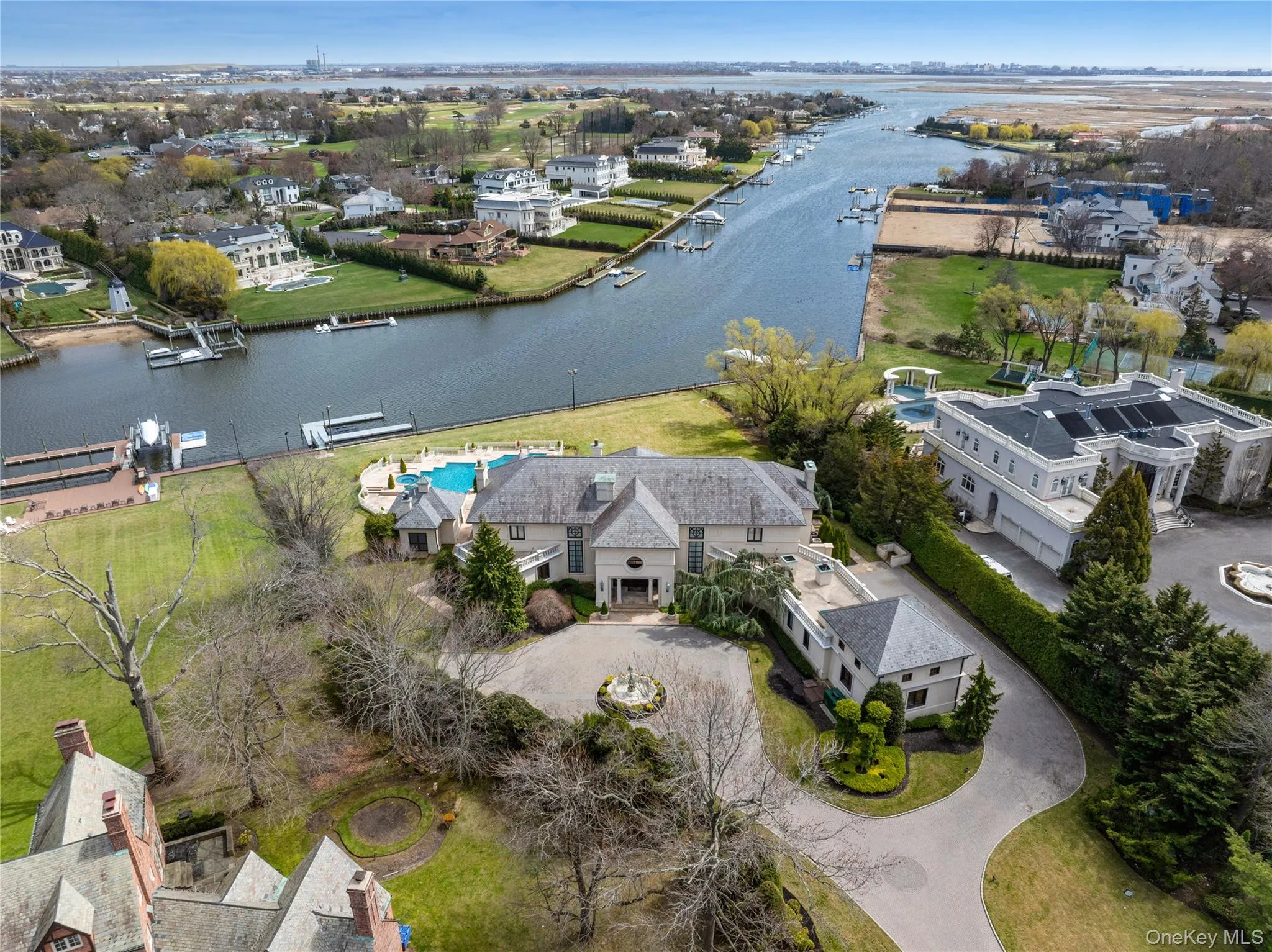 Waterfront estate featuring a circular driveway, an in-ground swimming pool, a private dock, and manicured grounds Waterfront estate featuring a circular driveway, an in-ground swimming pool, a private dock, and manicured grounds