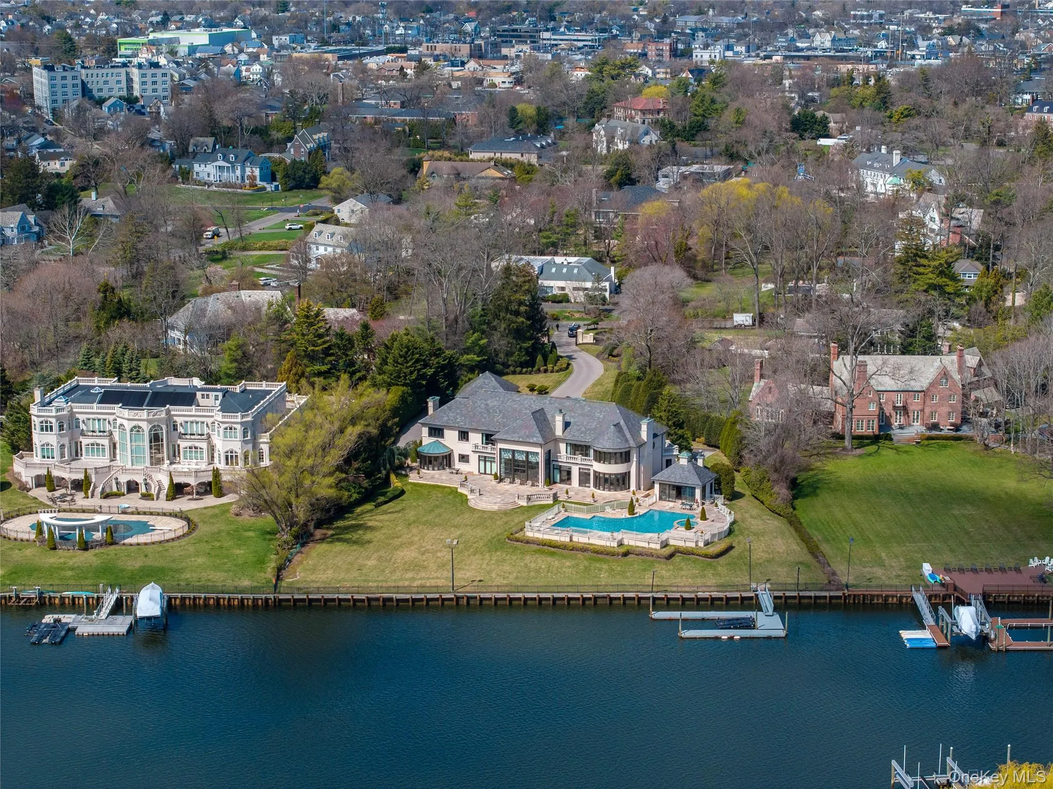 Waterfront property featuring a private boat dock, an in-ground swimming pool, a spacious lawn, a paved driveway, and established landscaping Waterfront property featuring a private boat dock, an in-ground swimming pool, a spacious lawn, a paved driveway, and established landscaping