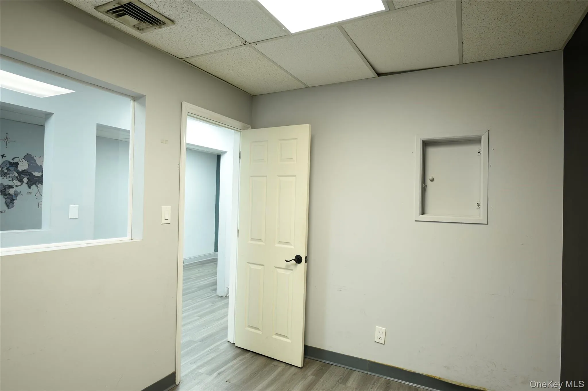 Interior room featuring wood-finish flooring, light gray wall paint, and a dropped ceiling with recessed lighting Interior room featuring wood-finish flooring, light gray wall paint, and a dropped ceiling with recessed lighting
