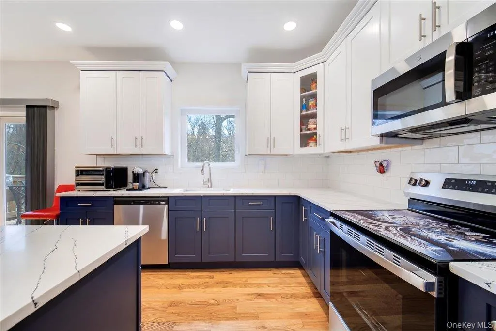 Modern kitchen featuring two-tone cabinetry with white upper and navy lower cabinets, white subway tile backsplash, and light wood-finish flooring Modern kitchen featuring two-tone cabinetry with white upper and navy lower cabinets, white subway tile backsplash, and light wood-finish flooring