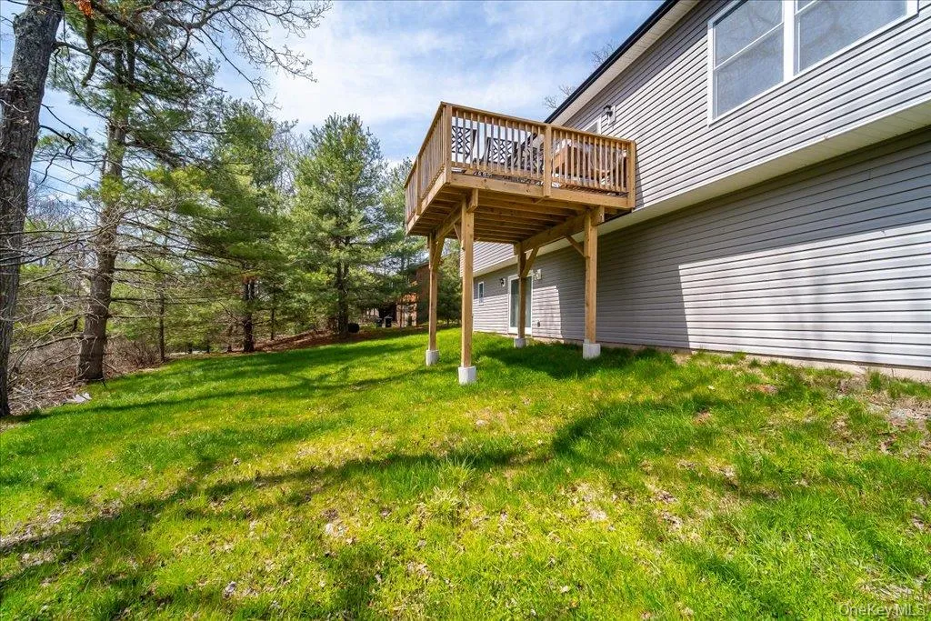 Elevated wooden deck structure with a slatted railing, featuring grey horizontal siding and multiple windows Elevated wooden deck structure with a slatted railing, featuring grey horizontal siding and multiple windows