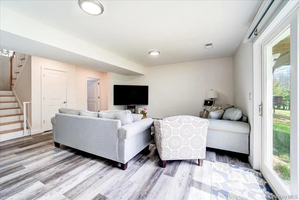 Spacious lower-level living area with wood-finish flooring and recessed lighting Spacious lower-level living area with wood-finish flooring and recessed lighting