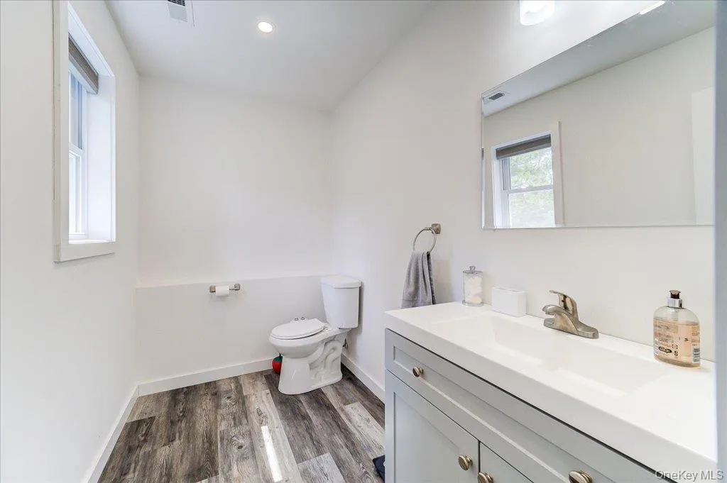 Modern bathroom featuring a contemporary vanity with an integrated sink, brushed nickel faucet, and wood-finish flooring Modern bathroom featuring a contemporary vanity with an integrated sink, brushed nickel faucet, and wood-finish flooring