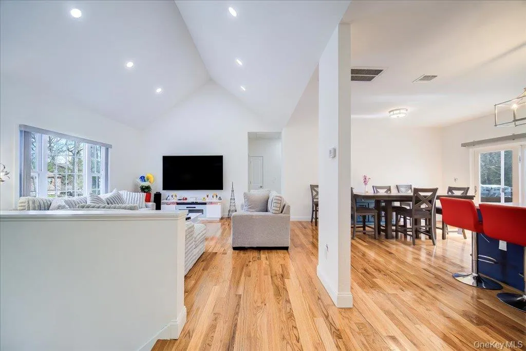 Spacious living area featuring a vaulted ceiling with recessed lighting and expansive windows Spacious living area featuring a vaulted ceiling with recessed lighting and expansive windows