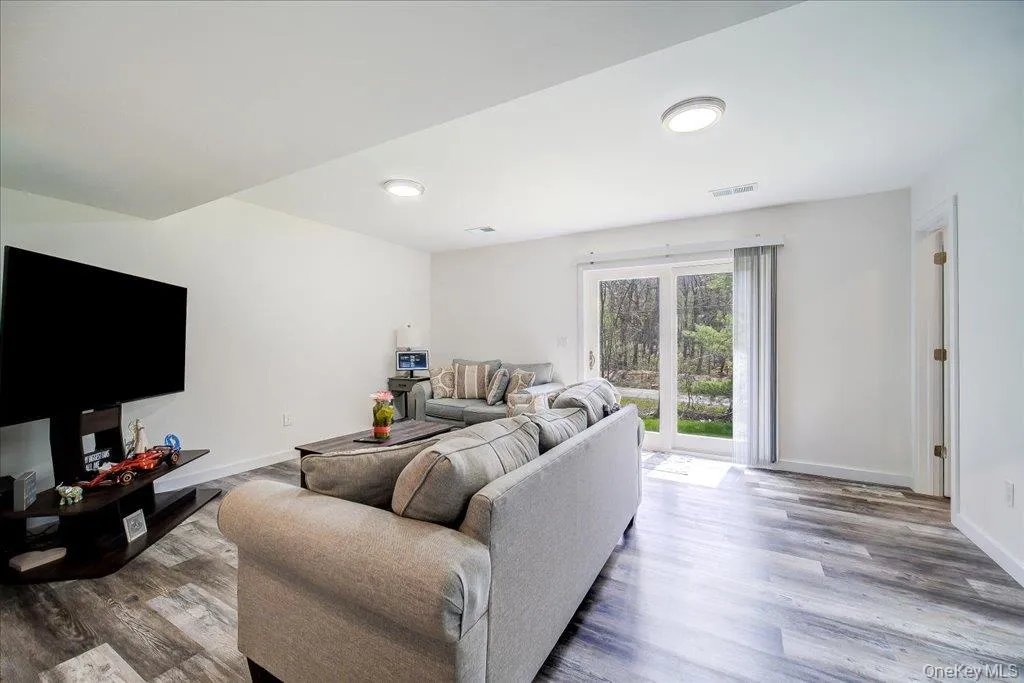 Spacious living area featuring light wood-finish flooring, recessed lighting, and a sliding glass door Spacious living area featuring light wood-finish flooring, recessed lighting, and a sliding glass door