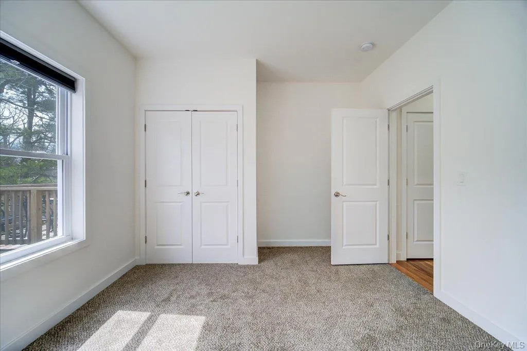 Carpeted room featuring white walls, a double-door closet, and an operable window Carpeted room featuring white walls, a double-door closet, and an operable window