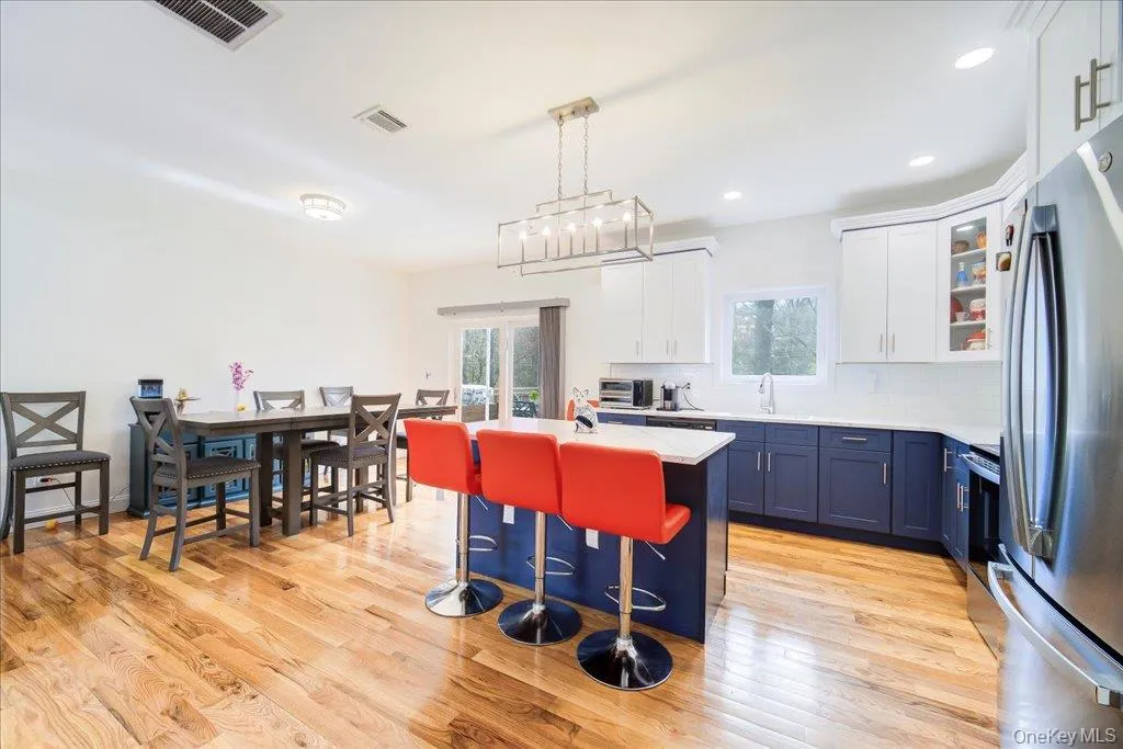 Spacious kitchen featuring wood-finish flooring, a central island with white countertop, and two-tone cabinetry Spacious kitchen featuring wood-finish flooring, a central island with white countertop, and two-tone cabinetry