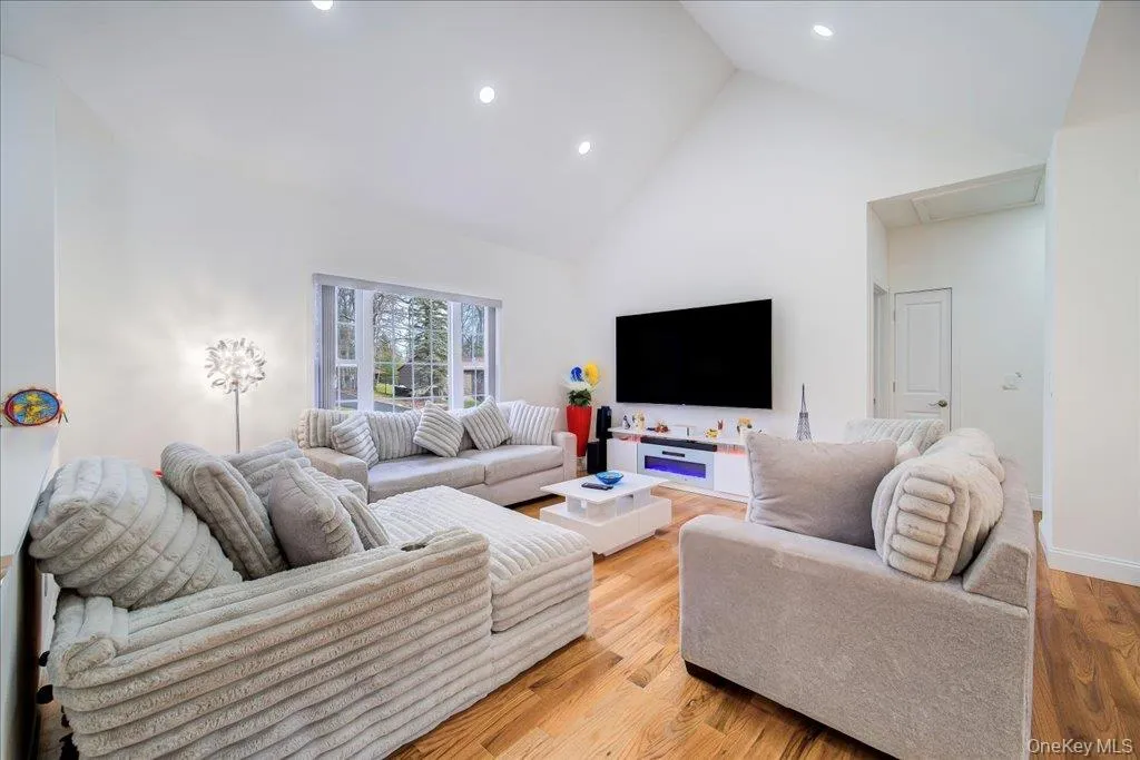 Vaulted ceilings enhance this living area featuring wood-finish flooring and recessed lighting Vaulted ceilings enhance this living area featuring wood-finish flooring and recessed lighting