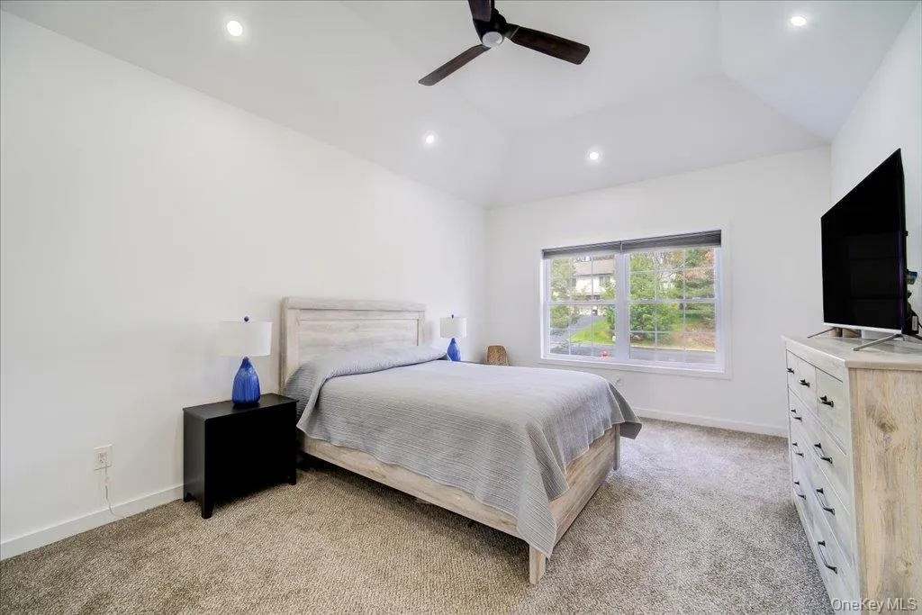 Vaulted ceiling room featuring recessed lighting, a ceiling fan, a large window, and carpeted flooring Vaulted ceiling room featuring recessed lighting, a ceiling fan, a large window, and carpeted flooring