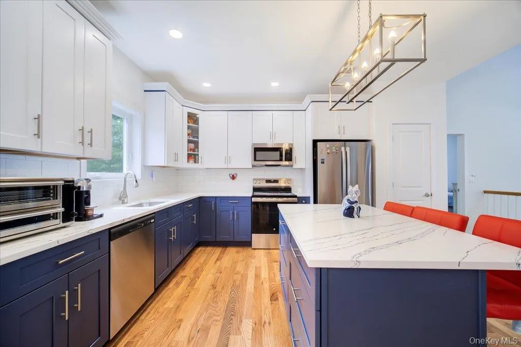 Contemporary kitchen featuring two-tone cabinetry, stainless steel appliances, and wood-finish flooring Contemporary kitchen featuring two-tone cabinetry, stainless steel appliances, and wood-finish flooring