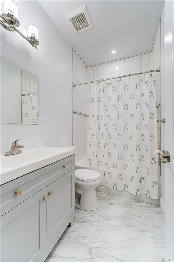 Bathroom featuring a gray vanity with an integrated sink, brushed nickel faucet, and gold-tone hardware Bathroom featuring a gray vanity with an integrated sink, brushed nickel faucet, and gold-tone hardware