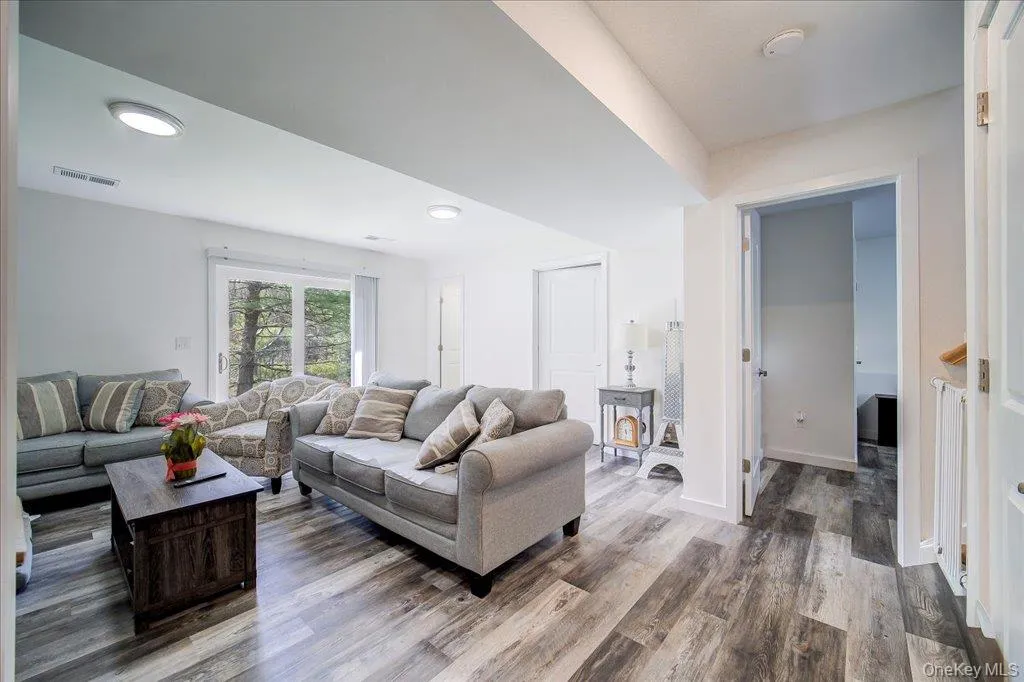 Spacious living area featuring wood-finish flooring, recessed lighting, and a large window with outdoor views Spacious living area featuring wood-finish flooring, recessed lighting, and a large window with outdoor views