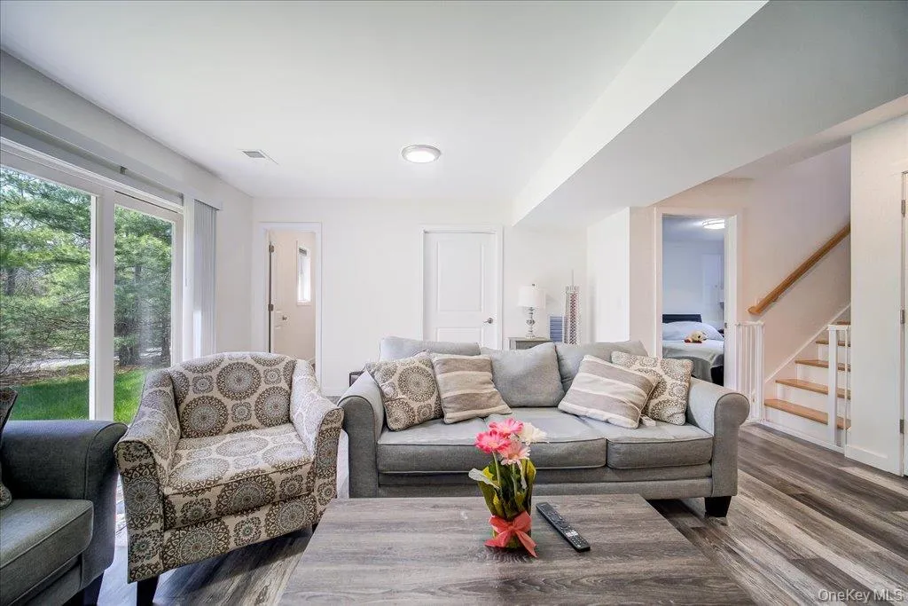Spacious living area featuring wood-finish flooring, recessed lighting, and large glass sliding doors providing exterior access Spacious living area featuring wood-finish flooring, recessed lighting, and large glass sliding doors providing exterior access
