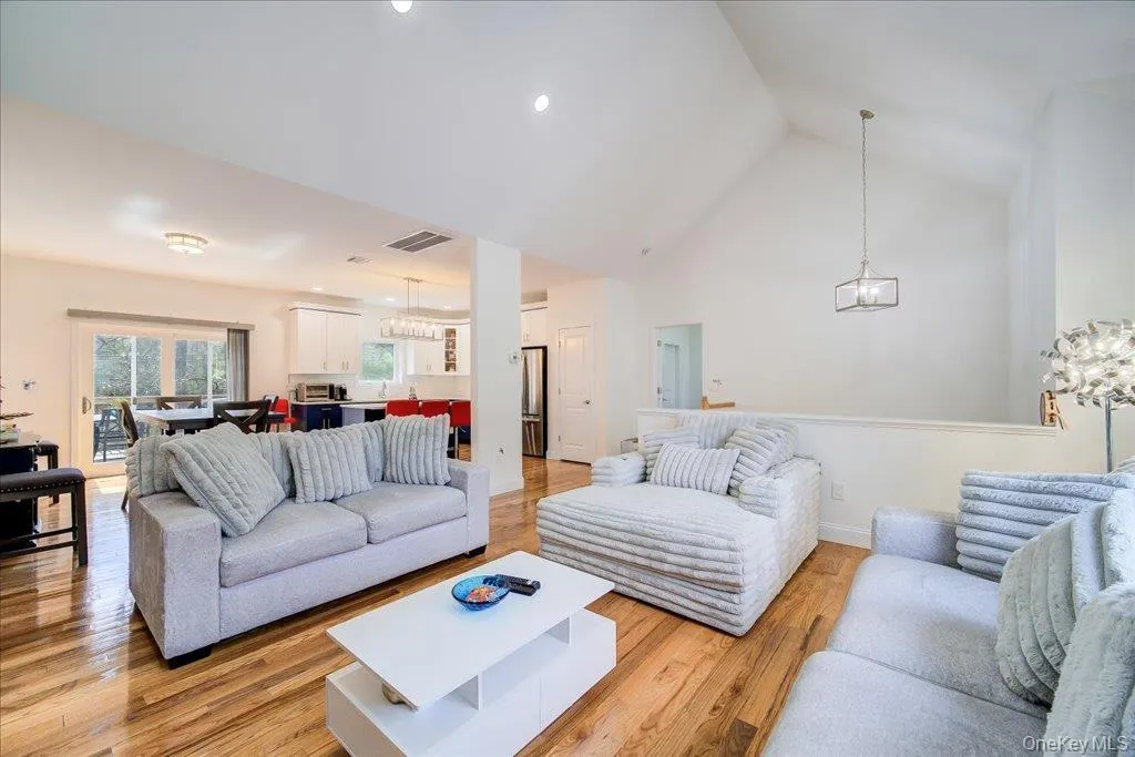 Spacious living area featuring polished wood-finish flooring and a soaring vaulted ceiling Spacious living area featuring polished wood-finish flooring and a soaring vaulted ceiling