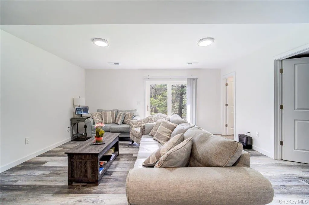 Spacious room featuring wood-finish flooring, white walls, and recessed lighting Spacious room featuring wood-finish flooring, white walls, and recessed lighting