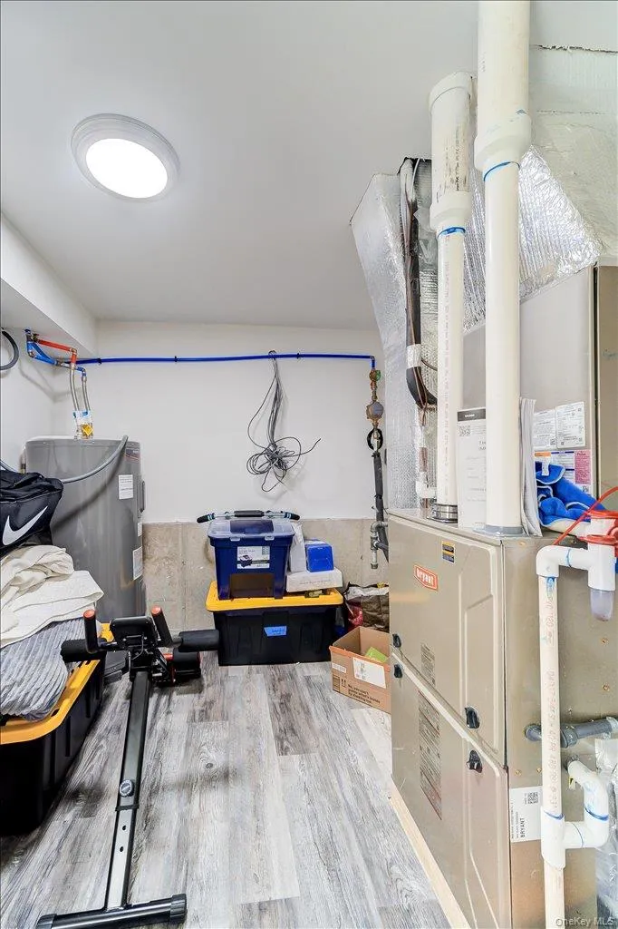 Dedicated utility area featuring a water heater, furnace, and wood-finish flooring Dedicated utility area featuring a water heater, furnace, and wood-finish flooring
