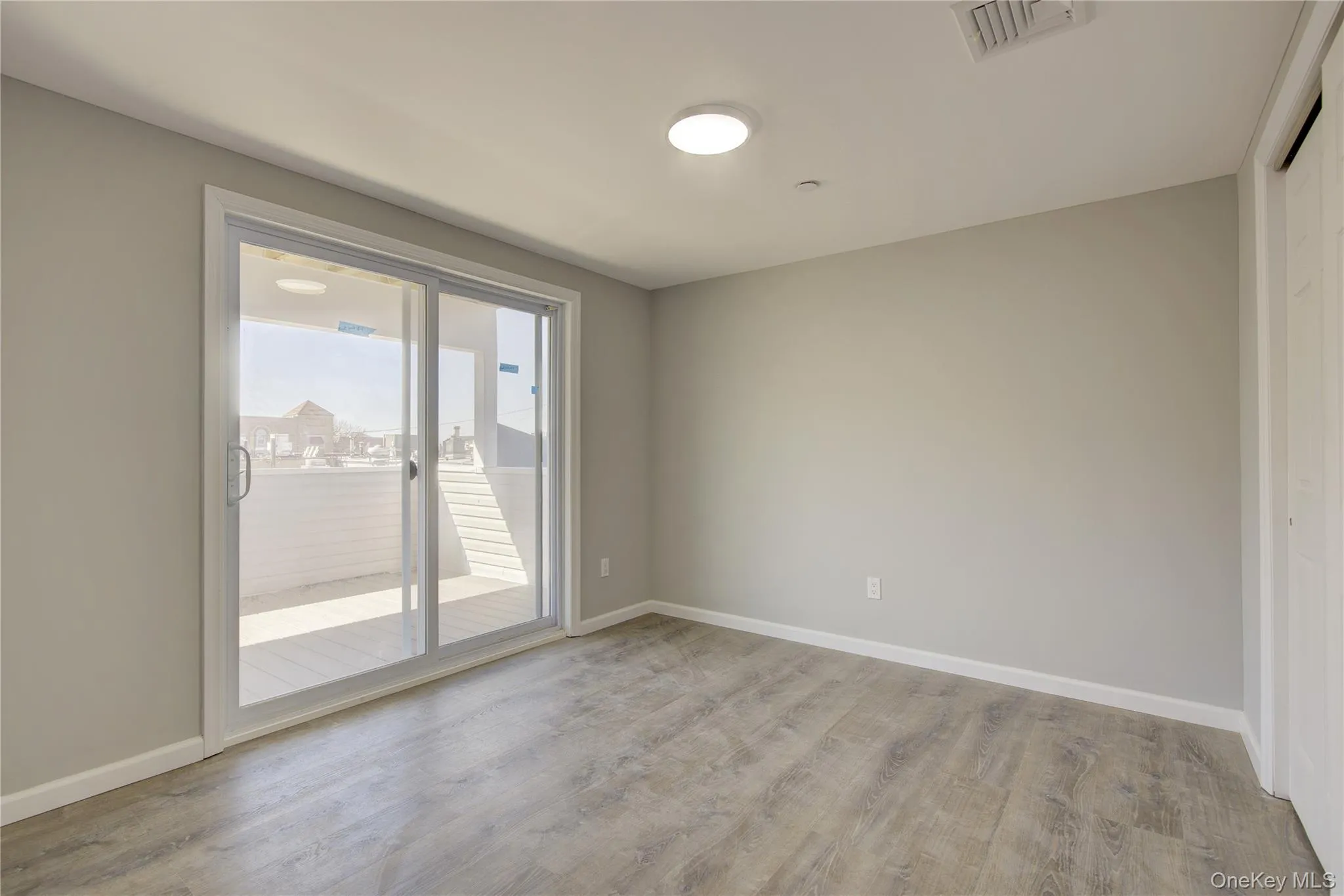 Empty room with light wood finished floors, visible vents, and baseboards Empty room with light wood finished floors, visible vents, and baseboards