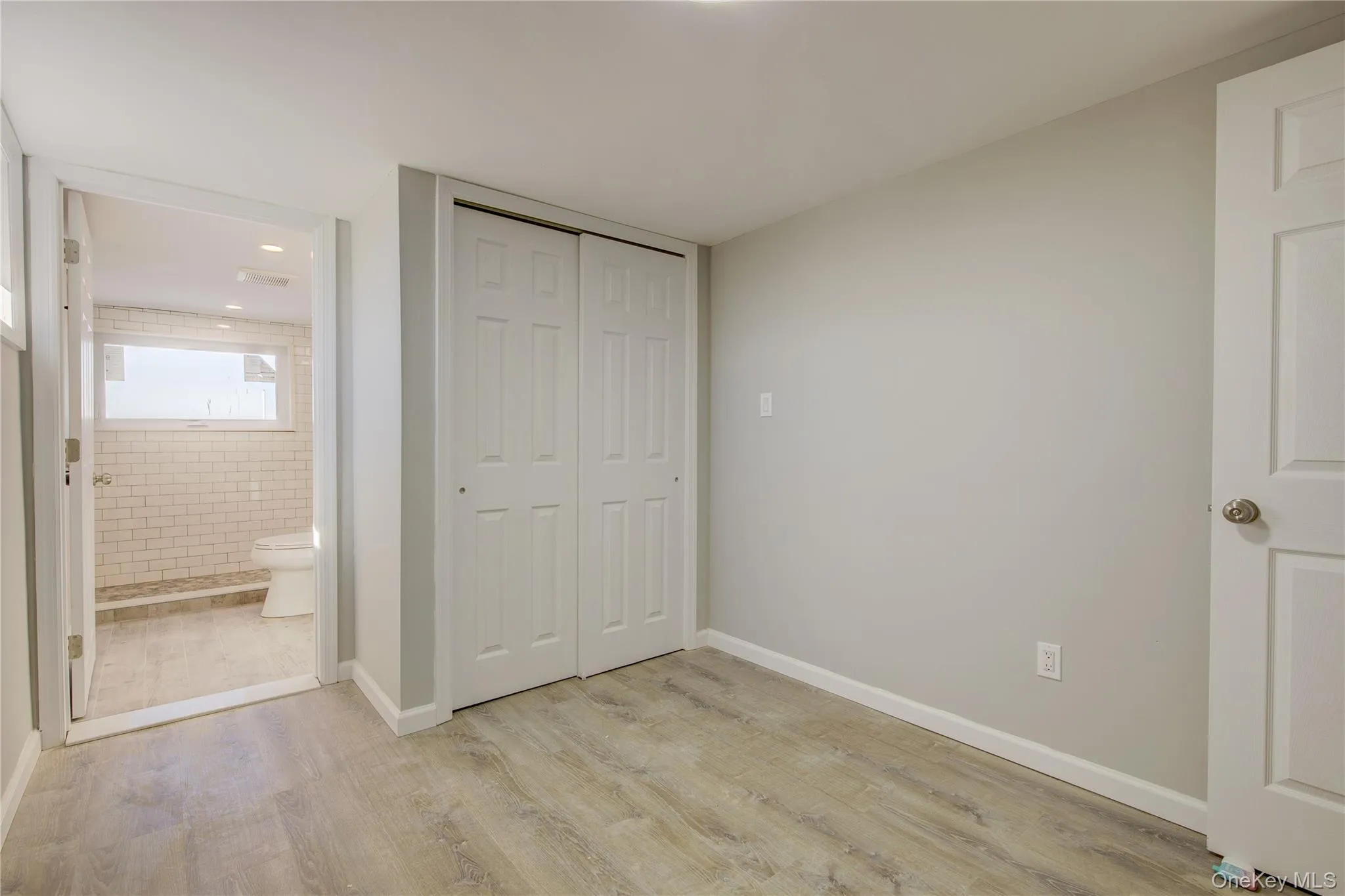 Unfurnished bedroom with light wood finished floors, connected bathroom, a closet, and baseboards Unfurnished bedroom with light wood finished floors, connected bathroom, a closet, and baseboards