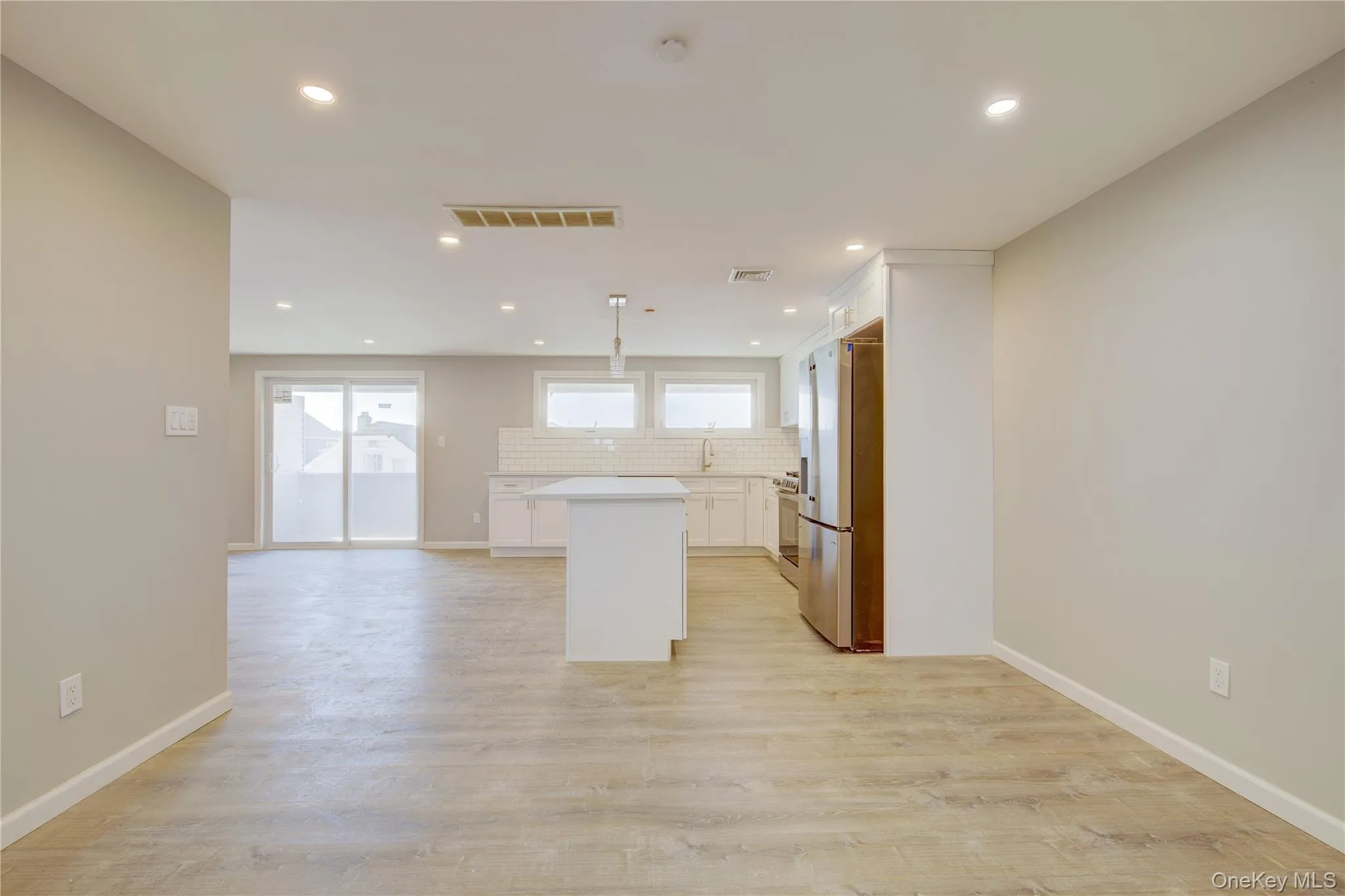 Kitchen featuring visible vents, decorative backsplash, white cabinetry, light wood-type flooring, and a center island Kitchen featuring visible vents, decorative backsplash, white cabinetry, light wood-type flooring, and a center island
