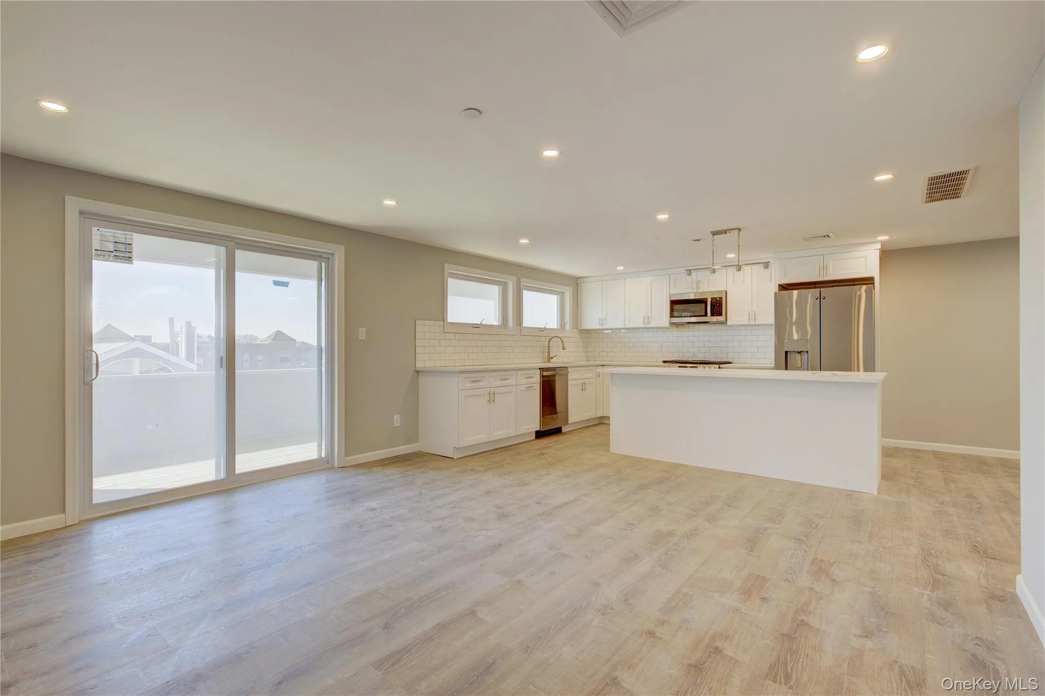 Unfurnished living room featuring recessed lighting, visible vents, light wood-style floors, and a healthy amount of sunlight Unfurnished living room featuring recessed lighting, visible vents, light wood-style floors, and a healthy amount of sunlight