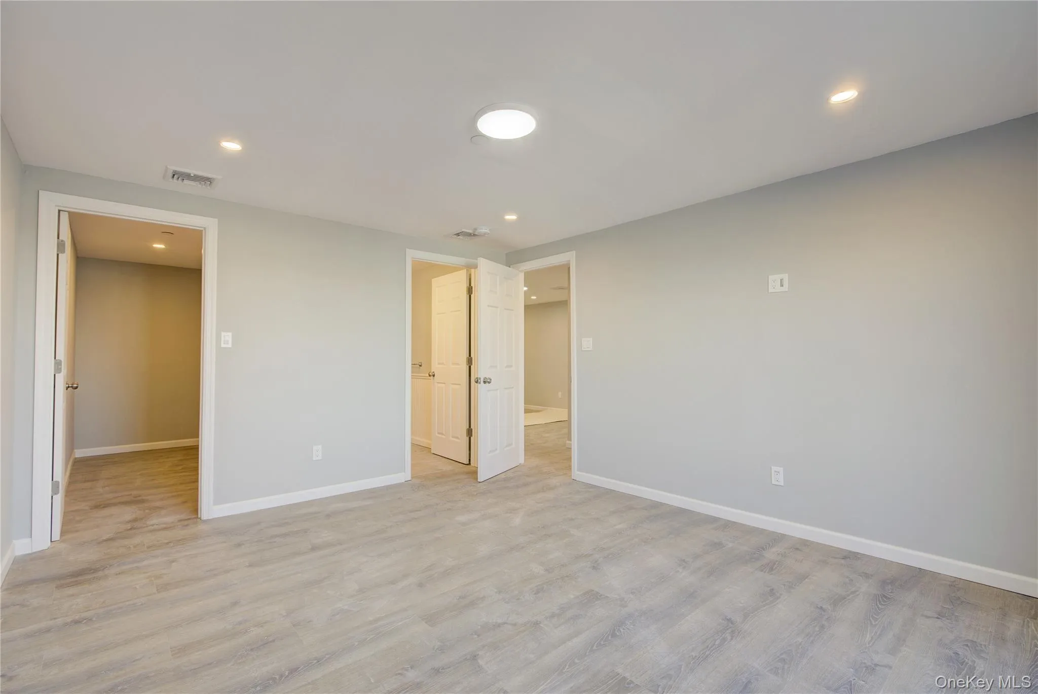 Spare room featuring light wood finished floors, visible vents, and baseboards Spare room featuring light wood finished floors, visible vents, and baseboards