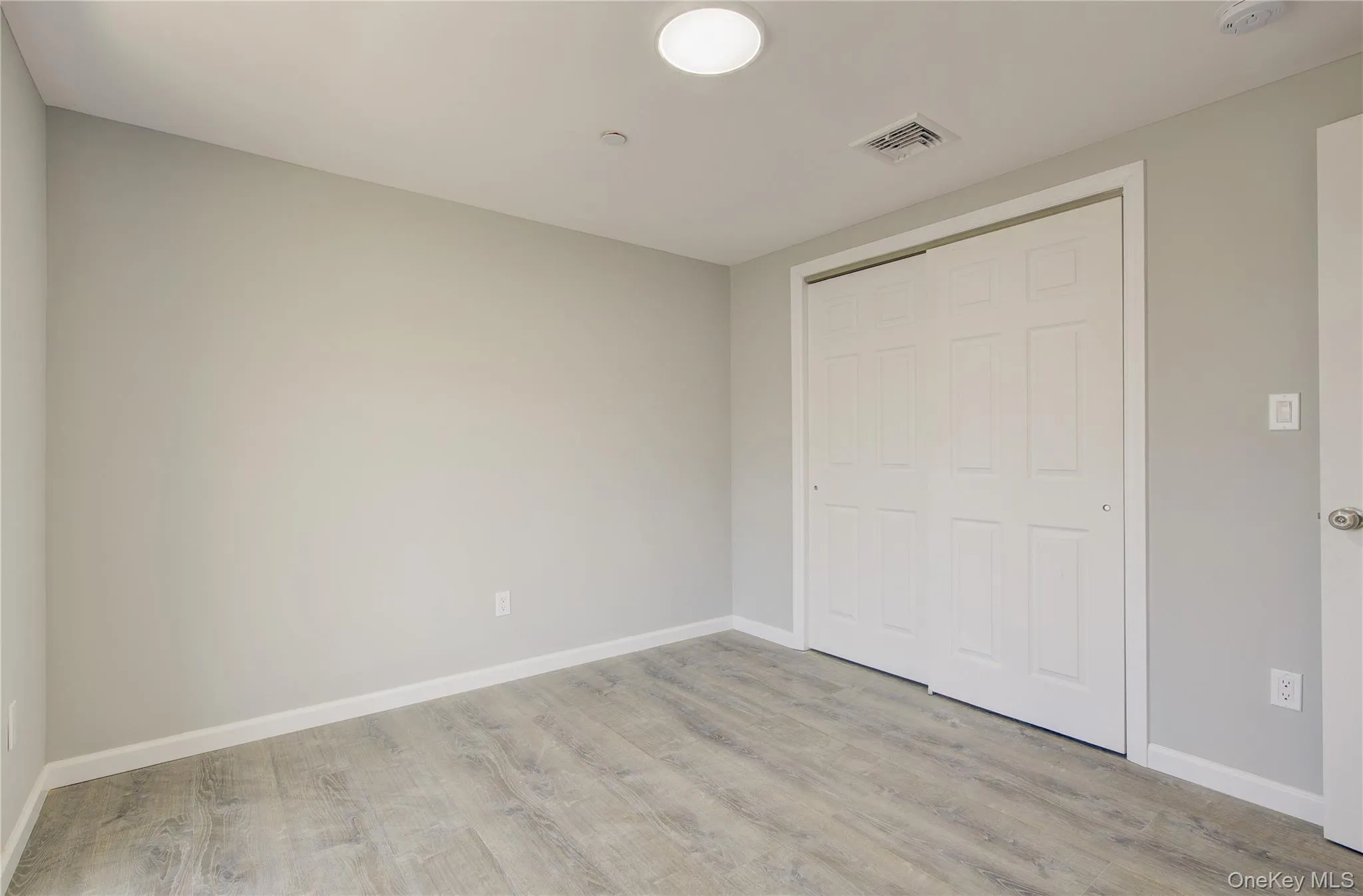 Unfurnished bedroom with visible vents, baseboards, a closet, and wood finished floors Unfurnished bedroom with visible vents, baseboards, a closet, and wood finished floors
