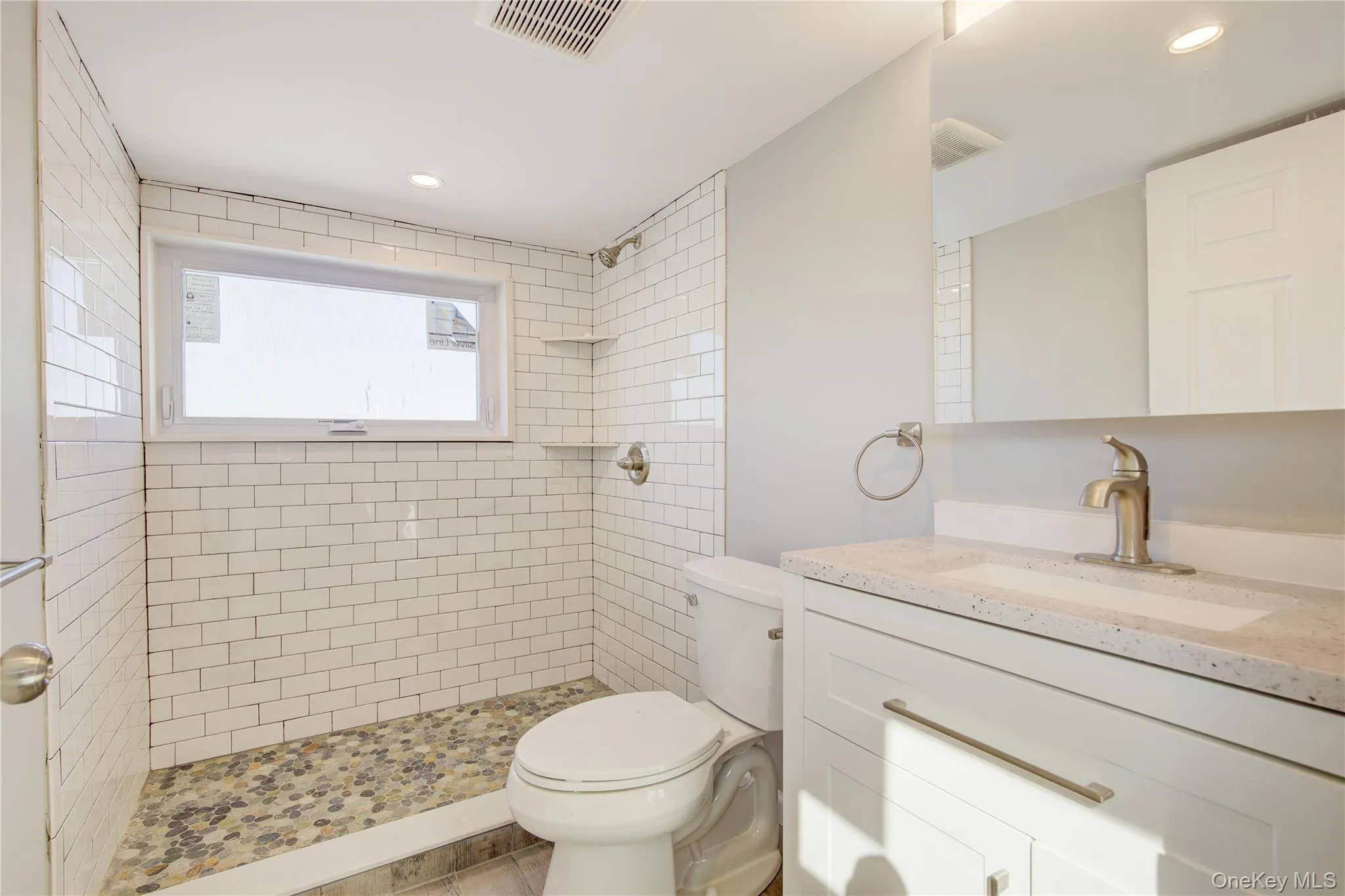 Bathroom with vanity, toilet, visible vents, and tiled shower Bathroom with vanity, toilet, visible vents, and tiled shower