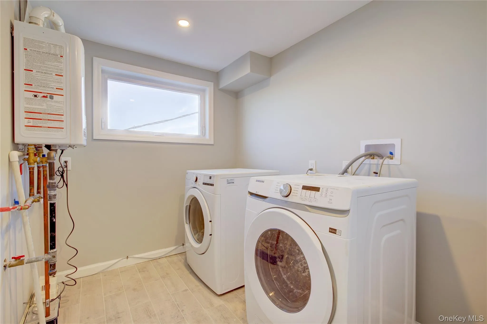 Clothes washing area featuring washer and dryer, recessed lighting, light wood finished floors, baseboards, and laundry area Clothes washing area featuring washer and dryer, recessed lighting, light wood finished floors, baseboards, and laundry area