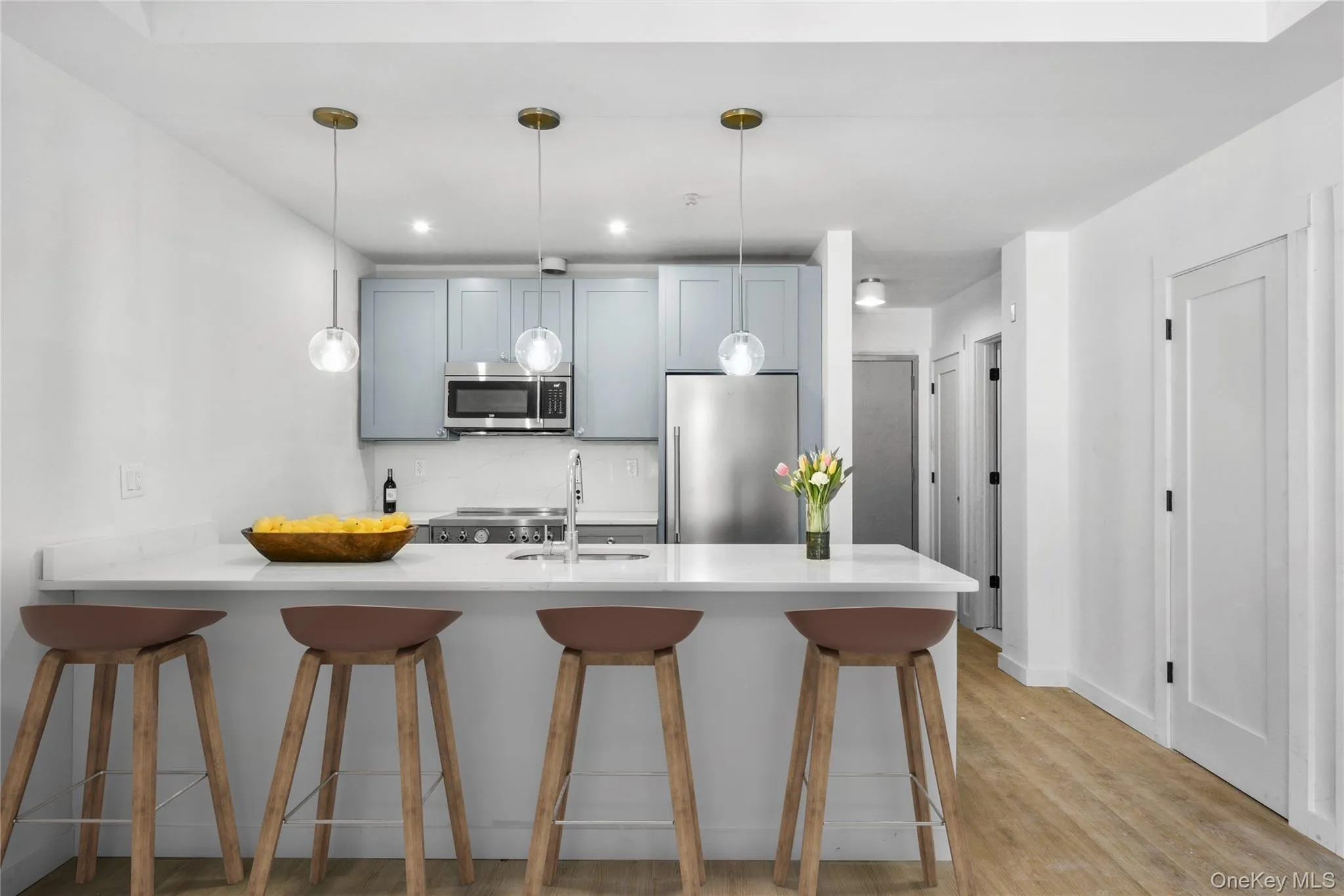 Kitchen featuring stainless steel appliances, a breakfast bar, a sink, light countertops, and decorative light fixtures Kitchen featuring stainless steel appliances, a breakfast bar, a sink, light countertops, and decorative light fixtures