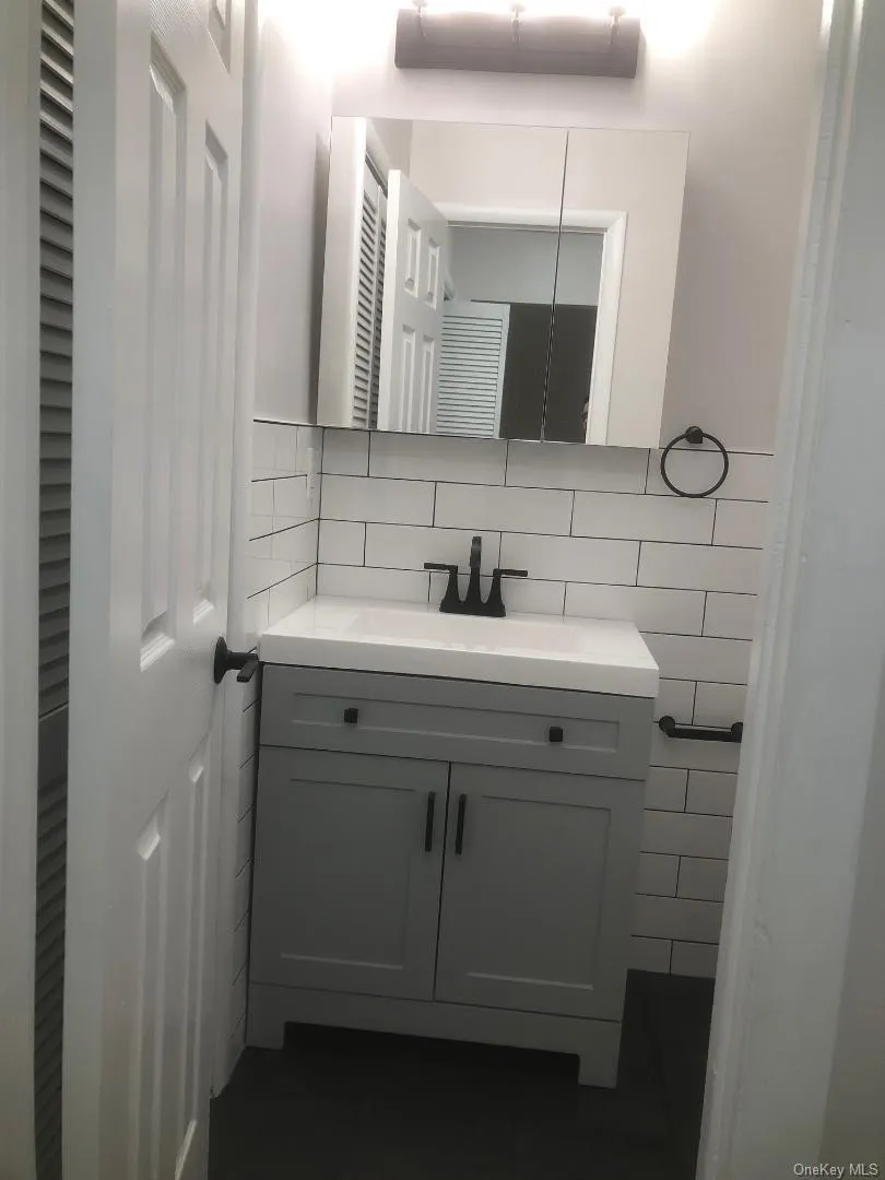Pretty updated bathroom which features a vanity featuring a light gray shaker-style cabinet, integrated sink, and matte black hardware Pretty updated bathroom which features a vanity featuring a light gray shaker-style cabinet, integrated sink, and matte black hardware