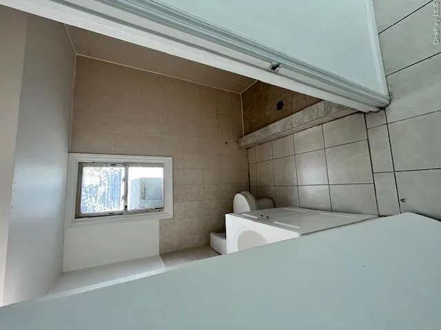 Bathroom with floor-to-ceiling tile in the shower area, a single window, tiled flooring, and a white vanity with an integrated sink Bathroom with floor-to-ceiling tile in the shower area, a single window, tiled flooring, and a white vanity with an integrated sink