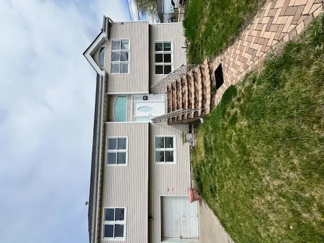 Split-level residence featuring light-colored siding and a dark shingle roof Split-level residence featuring light-colored siding and a dark shingle roof