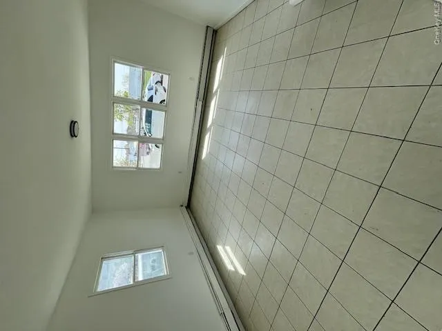 Spacious room featuring light-colored square floor tiles, white painted walls, and baseboard heating Spacious room featuring light-colored square floor tiles, white painted walls, and baseboard heating