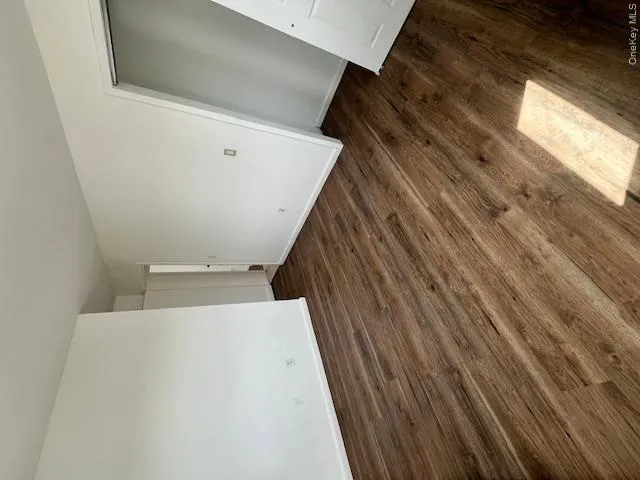 Room featuring light wood-finish flooring, white painted walls, and white baseboards Room featuring light wood-finish flooring, white painted walls, and white baseboards