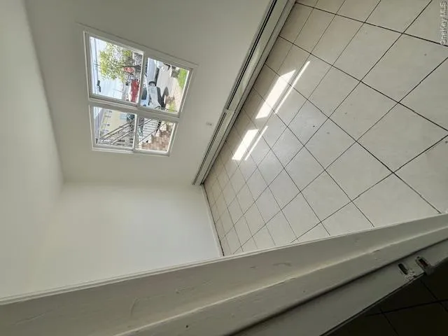 Room featuring tile flooring, white walls, and a large window Room featuring tile flooring, white walls, and a large window