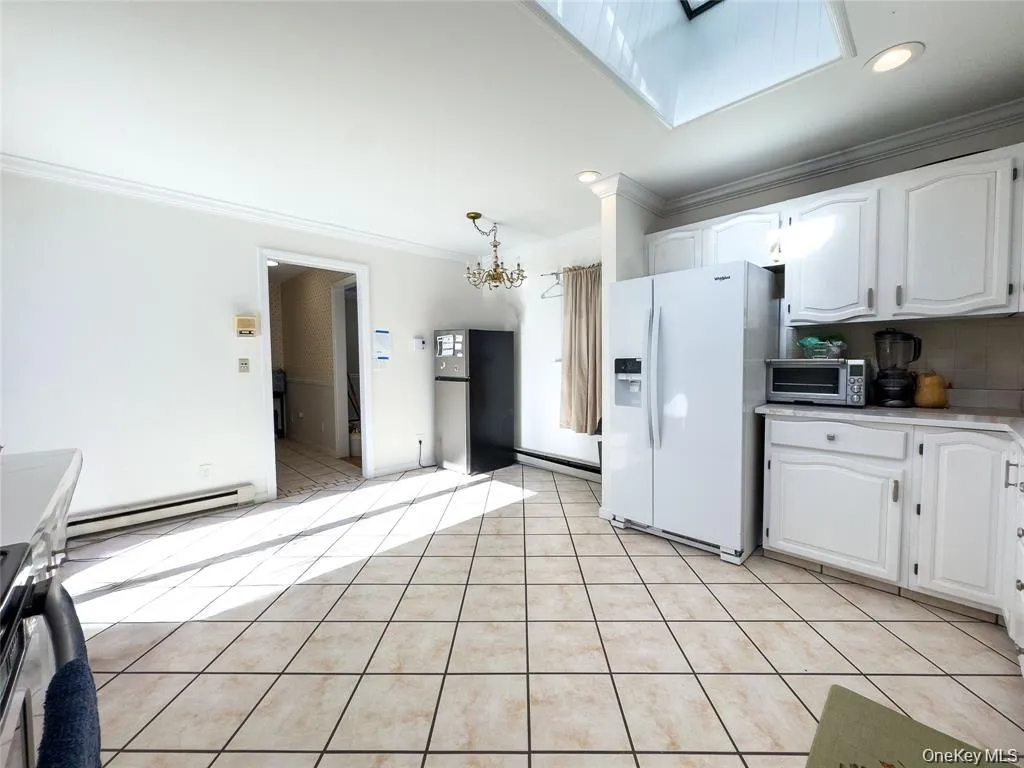 Kitchen featuring ceramic tile flooring, white cabinetry, a skylight, and recessed lighting Kitchen featuring ceramic tile flooring, white cabinetry, a skylight, and recessed lighting