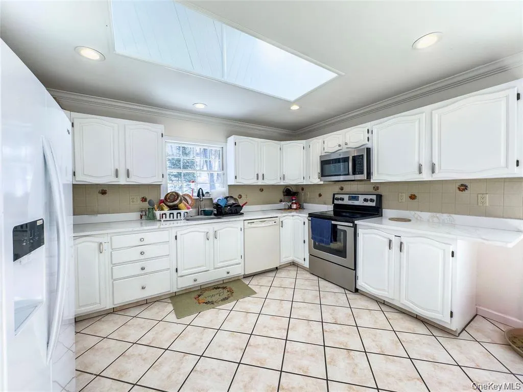 Kitchen featuring white cabinetry, light-toned countertops, a stainless steel range, and a built-in microwave Kitchen featuring white cabinetry, light-toned countertops, a stainless steel range, and a built-in microwave
