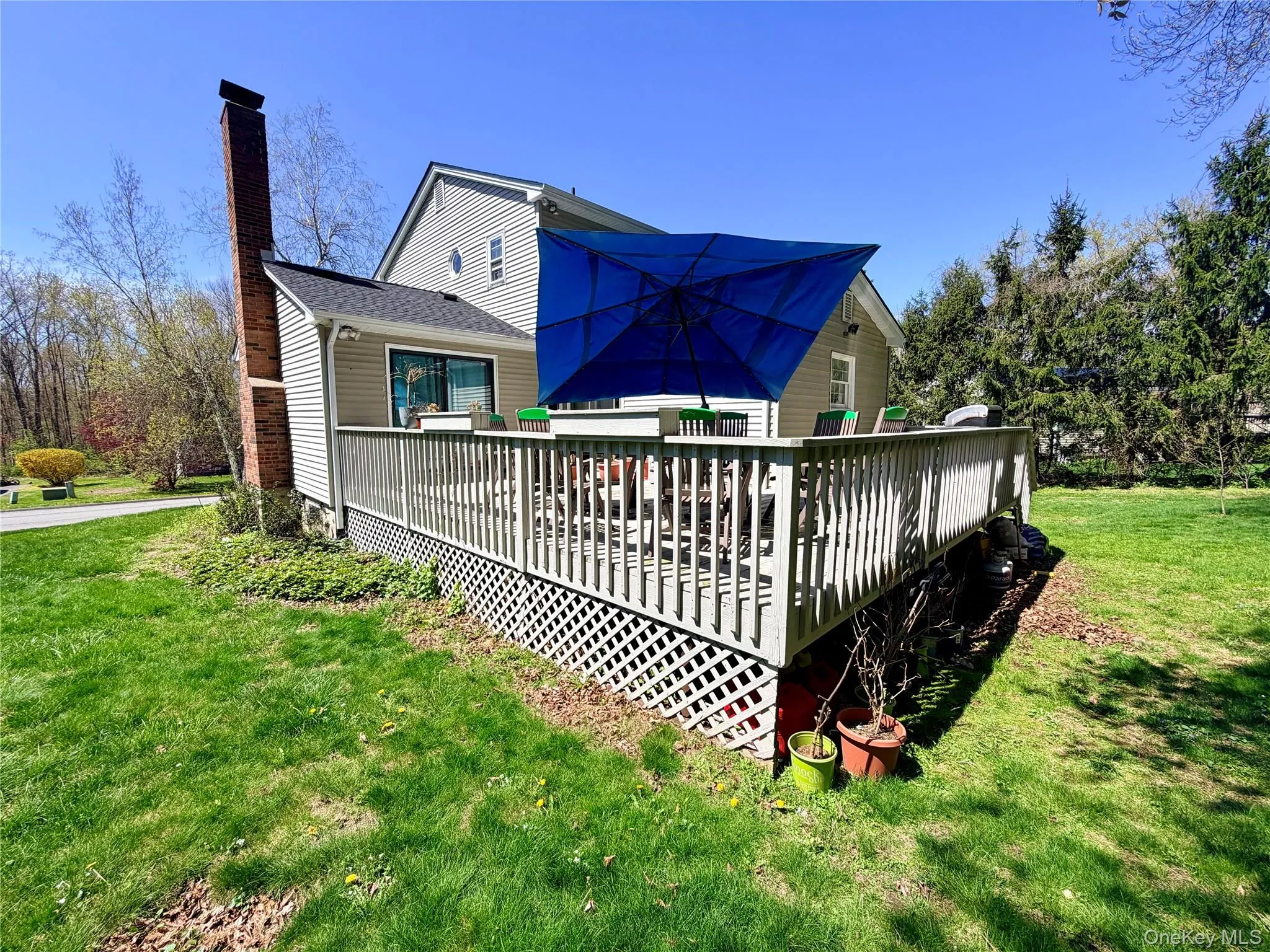 Expansive wood deck featuring a full-length railing and lattice skirting, accessed via a sliding glass door Expansive wood deck featuring a full-length railing and lattice skirting, accessed via a sliding glass door