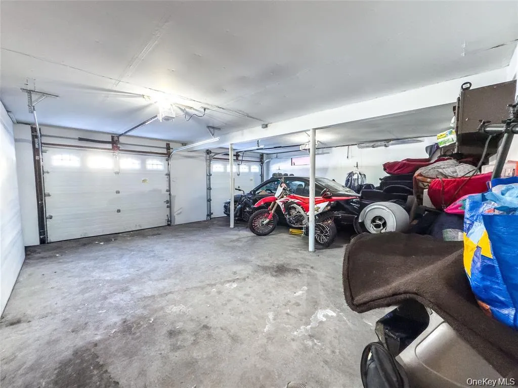 Spacious multi-bay garage featuring concrete flooring, multiple overhead garage doors with frosted window panels, and fluorescent lighting Spacious multi-bay garage featuring concrete flooring, multiple overhead garage doors with frosted window panels, and fluorescent lighting