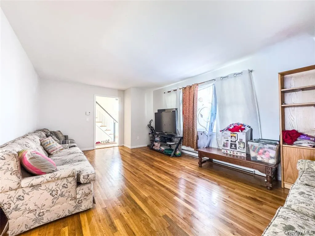 Living area featuring hardwood-finish flooring, white painted walls, and a window with natural light Living area featuring hardwood-finish flooring, white painted walls, and a window with natural light