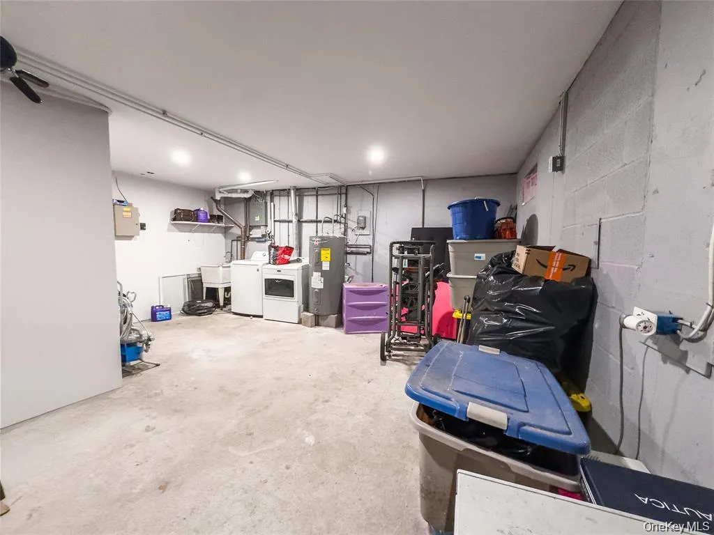 Utility room featuring concrete flooring, a laundry area with a washer and dryer, exposed piping, and overhead lighting Utility room featuring concrete flooring, a laundry area with a washer and dryer, exposed piping, and overhead lighting