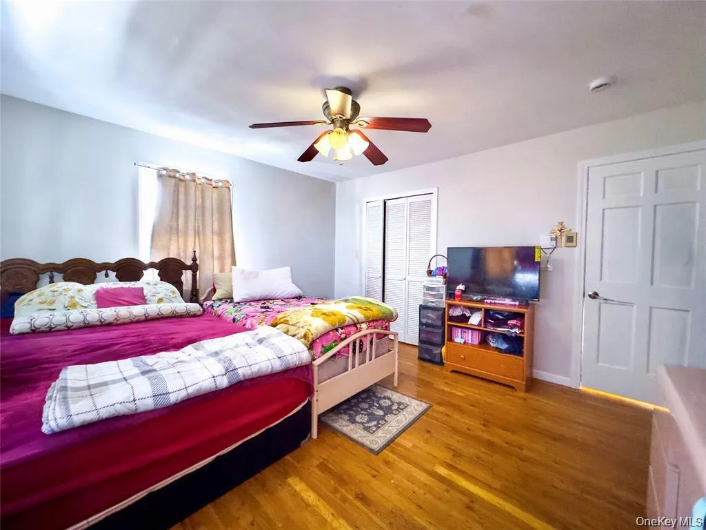 Bedroom featuring wood-finish flooring, a ceiling fan with integrated lighting, and a window with natural light Bedroom featuring wood-finish flooring, a ceiling fan with integrated lighting, and a window with natural light
