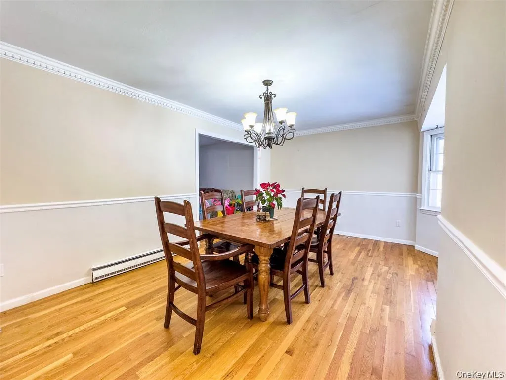 Dining area featuring wood-finish flooring, two-tone wall treatment, and decorative crown molding Dining area featuring wood-finish flooring, two-tone wall treatment, and decorative crown molding