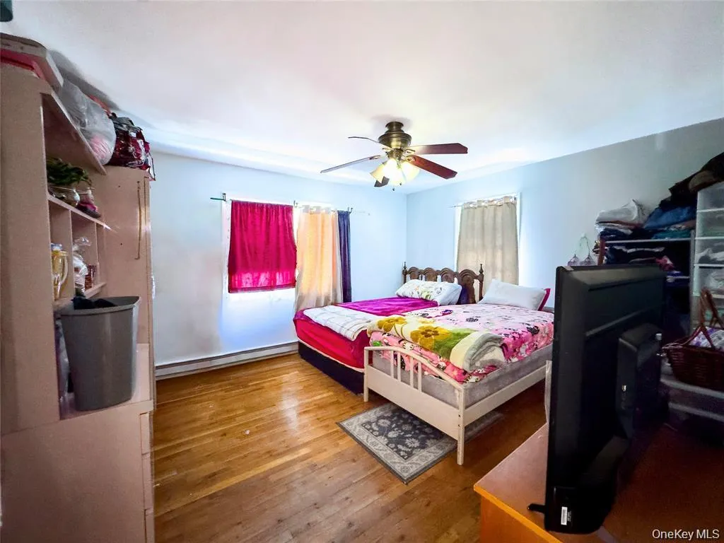 Bedroom featuring wood-finish flooring, two windows, and a ceiling fan with integrated lighting Bedroom featuring wood-finish flooring, two windows, and a ceiling fan with integrated lighting