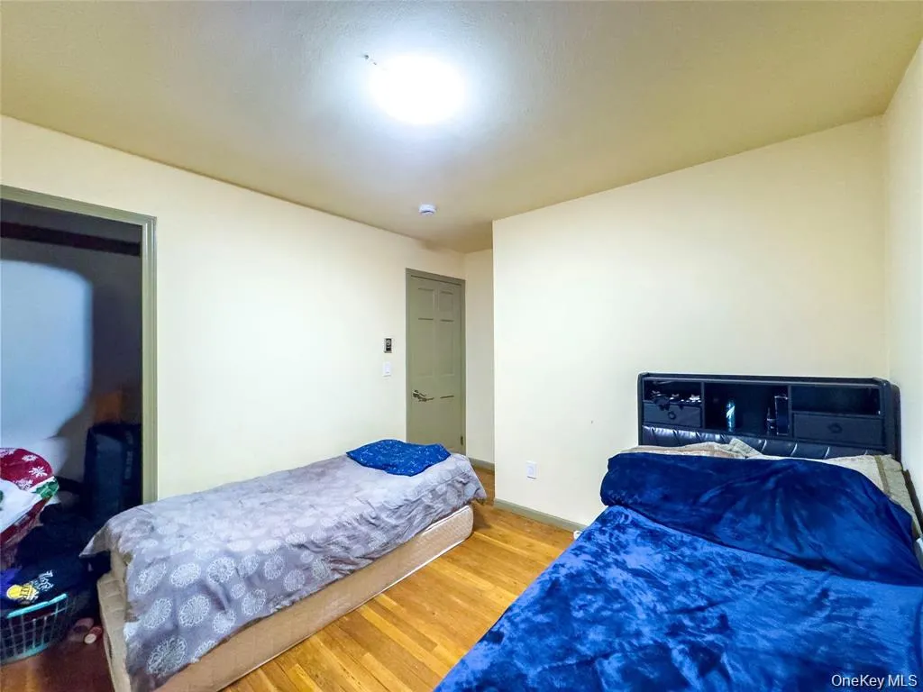 Interior room featuring wood-finish flooring, light-toned wall paint, and a flush-mount ceiling light Interior room featuring wood-finish flooring, light-toned wall paint, and a flush-mount ceiling light