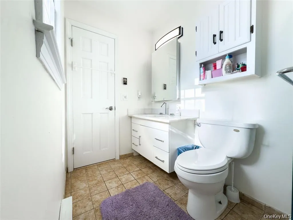 White vanity with a single sink and chrome faucet, under-cabinet storage, and an illuminated medicine cabinet White vanity with a single sink and chrome faucet, under-cabinet storage, and an illuminated medicine cabinet