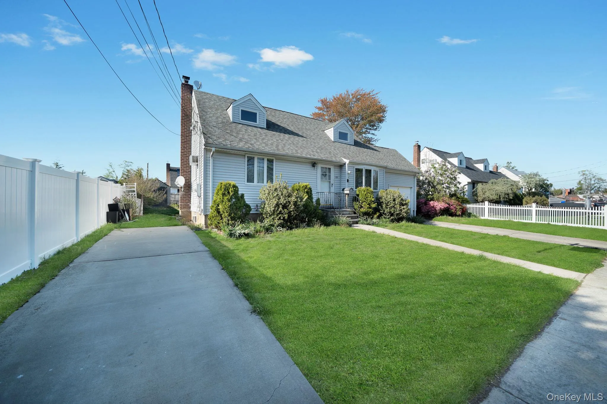 Traditional siding exterior featuring a prominent dormer window, an attached garage, a front lawn with established landscaping, and a concrete driveway Traditional siding exterior featuring a prominent dormer window, an attached garage, a front lawn with established landscaping, and a concrete driveway