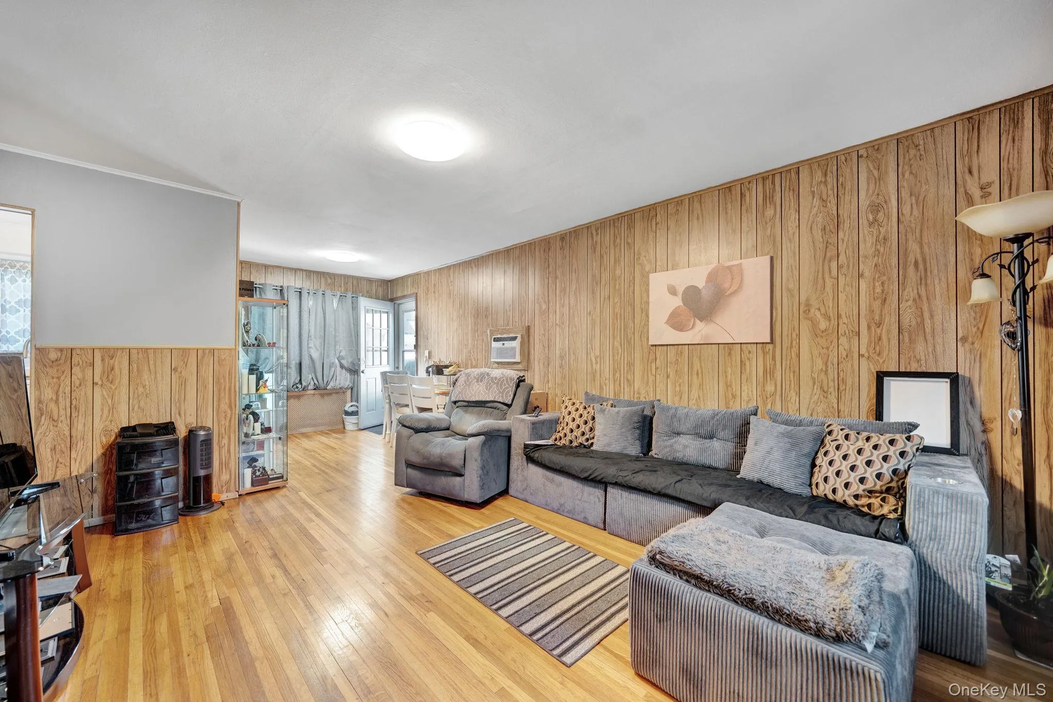 Spacious room featuring wood-finish paneling, light wood flooring, and a white ceiling 1st floor Spacious room featuring wood-finish paneling, light wood flooring, and a white ceiling 1st floor